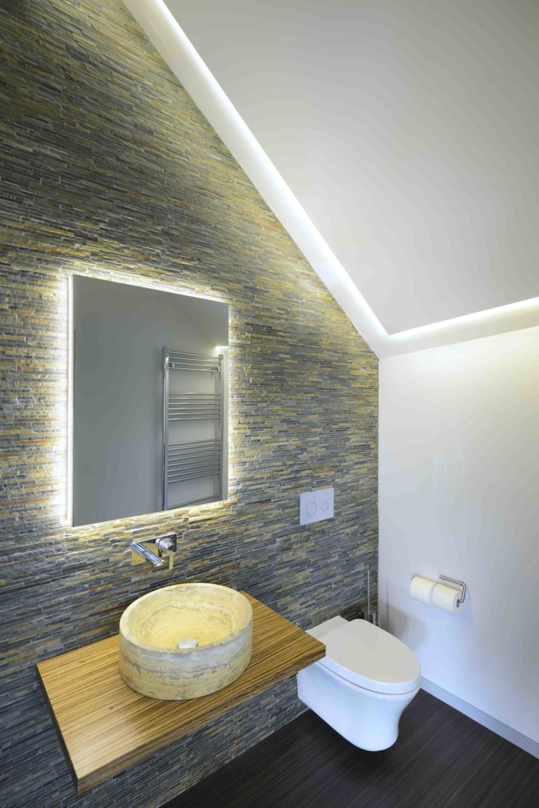 Bathroom with back lit mirror and round stone basin on stone tiled wall, Tigh Beag in the Cairngorms National Park